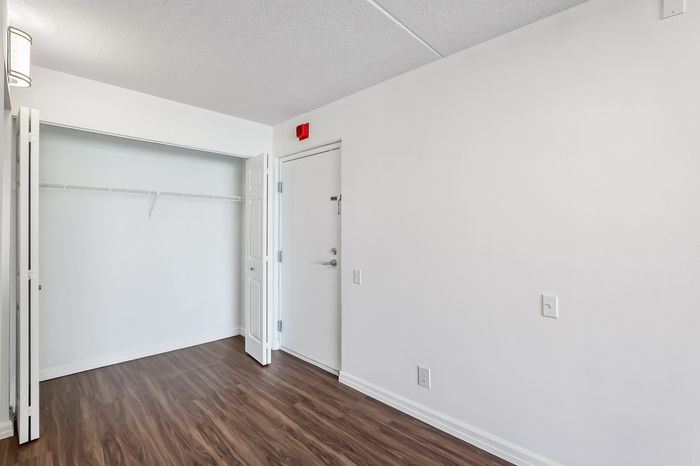 Cozy room with sleek wooden floors, bright white walls, and a spacious closet perfect for storage.