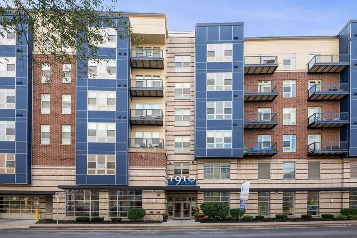 Modern apartment building with stylish brick and blue facade, featuring private balconies and large windows for natural light.