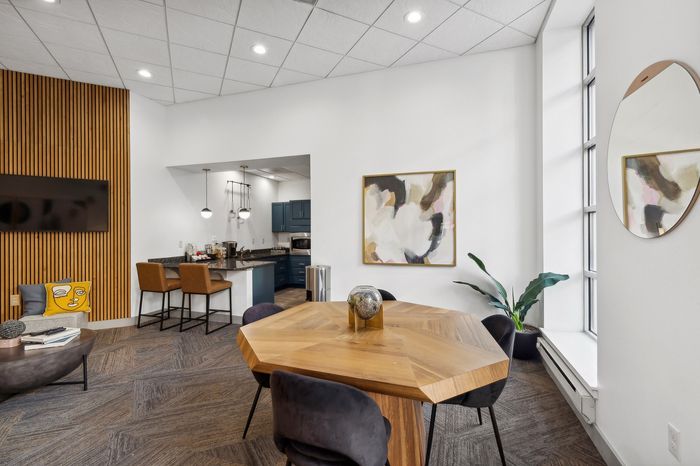 Modern and inviting apartment interior featuring a hexagonal wooden dining table, stylish seating, and a chic open kitchen with contemporary decor.