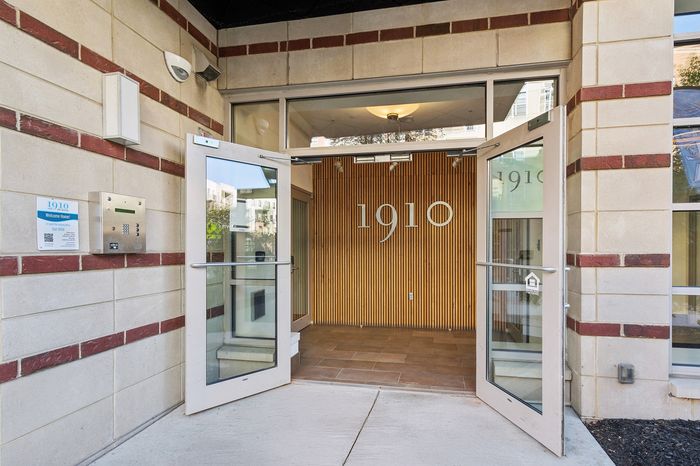 Inviting entrance with modern glass doors and stylish wood paneling, welcoming you to a contemporary apartment complex at number 1910.