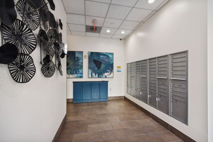 Contemporary apartment lobby with creative wall art, modern flooring, and convenient mailboxes.