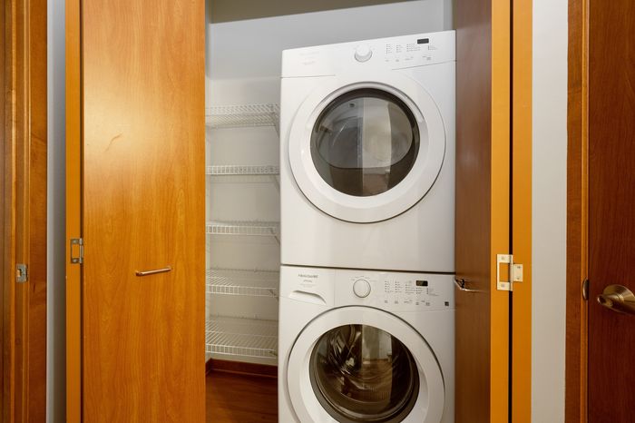 Modern apartment laundry area with stacked washer and dryer in a sleek wooden closet.