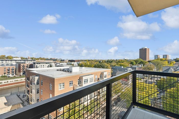 Breathtaking cityscape view from a modern apartment balcony, showcasing vibrant urban living and lush green surroundings.