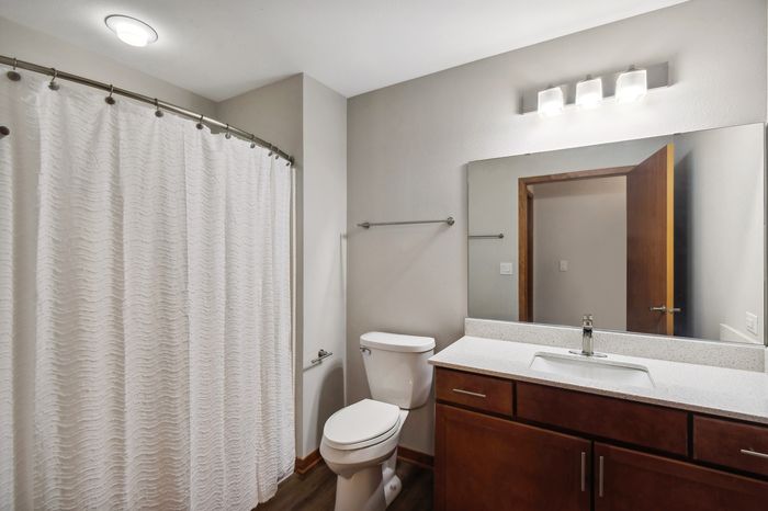 Modern bathroom with elegant fixtures, featuring a sleek countertop, spacious mirror, and stylish shower curtain.