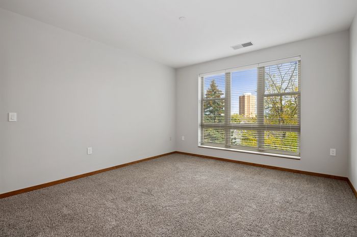 Bright and spacious bedroom with large windows offering scenic views, plush carpeting, and modern finishes.