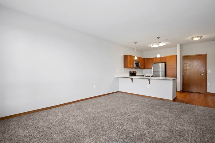 Bright and inviting open-concept living space featuring a modern kitchen with stainless steel appliances and warm wood cabinets.