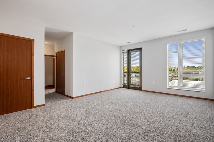 Bright and spacious apartment interior with large windows, plush carpet, and modern finishes, offering a cozy and welcoming atmosphere.