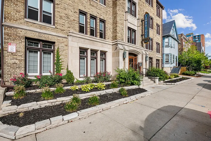 Charming historic building with elegant brick facade and vibrant garden, located on a picturesque urban street.