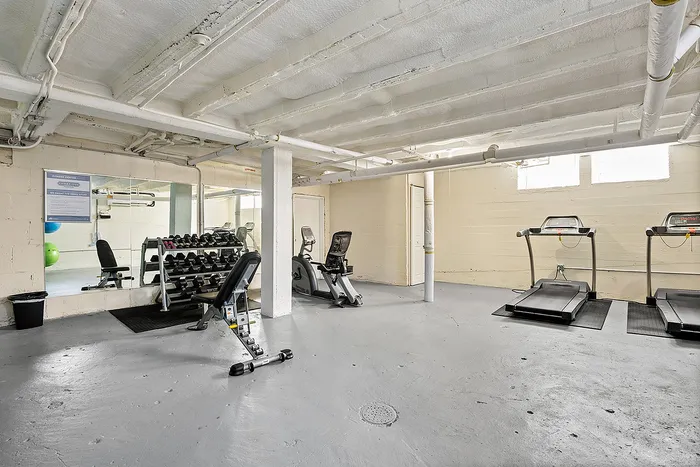 Modern, well-equipped gym with cardio machines, weight bench, and mirrored wall, inviting fitness enthusiasts.