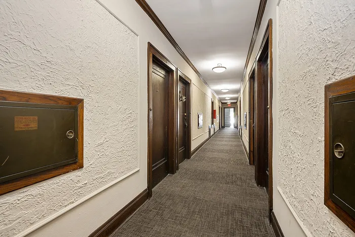 Elegant apartment corridor with warm wood accents, intricate textured walls, and soft ambient lighting.
