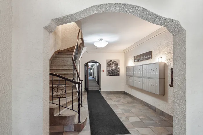 Inviting lobby with elegant staircase, modern mailboxes, and stylish artwork creating a warm welcome.