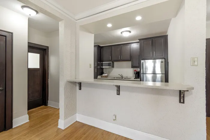 Inviting open kitchen concept with sleek dark cabinetry, stainless steel appliances, and a spacious breakfast bar perfect for modern living.