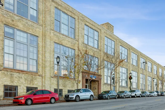 Charming urban building with classic brick facade and large industrial-style windows, perfect for modern city living.