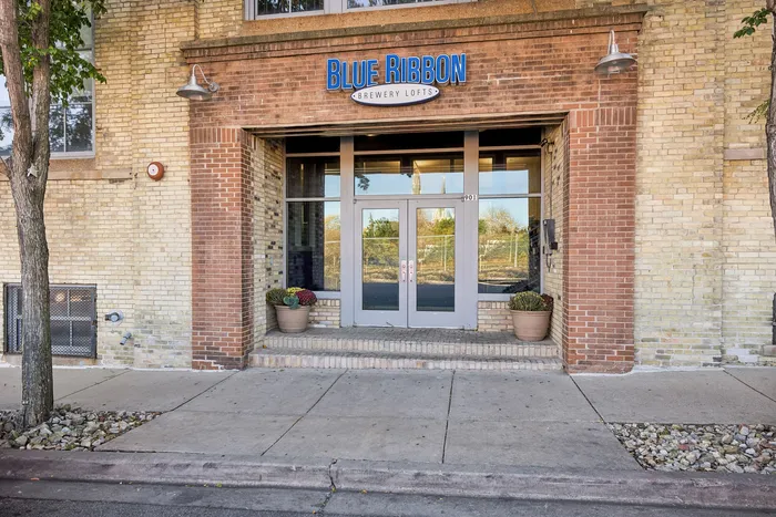 Inviting entrance to Blue Ribbon Brewery Lofts with charming brickwork and welcoming potted plants.