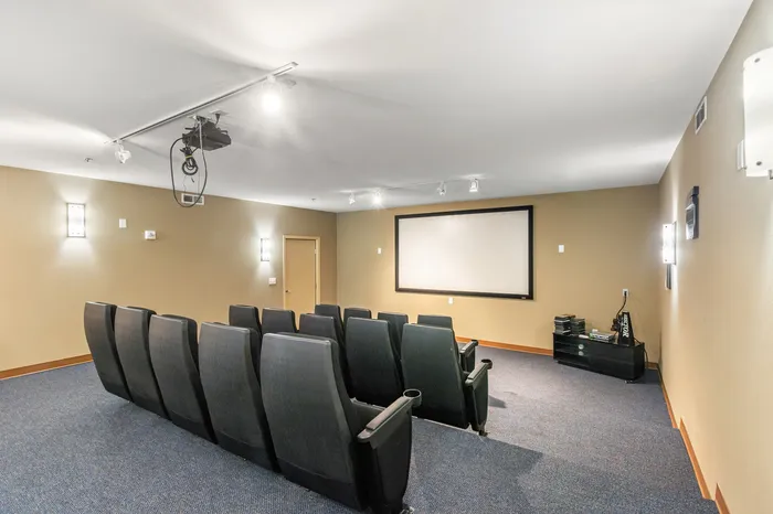 Modern apartment theater room with cozy seating, large screen, and ambient lighting for an exclusive movie experience.