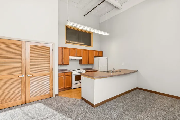 Bright and airy kitchen with wooden cabinetry, modern appliances, and an inviting breakfast bar in a stylish apartment.