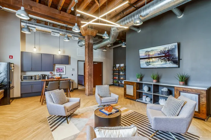 Chic modern loft with industrial charm featuring exposed beams, stylish seating area, open kitchen with sleek cabinetry, and vibrant decor.