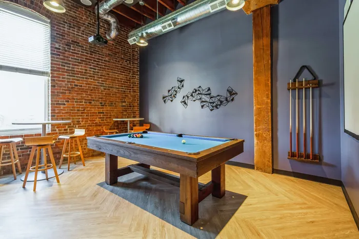 Chic entertainment room with a stylish pool table, modern brick wall, and elegant seating, perfect for social gatherings.