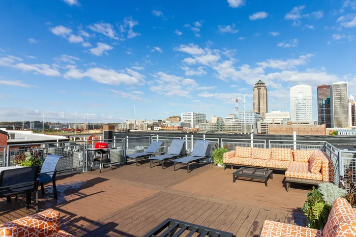 Chic rooftop terrace with stylish seating and lounge chairs, offering breathtaking skyline views under a bright blue sky.