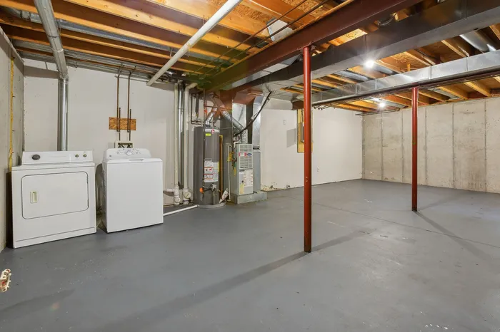 Spacious basement with laundry area, featuring washer, dryer, and modern utilities, perfect for storage or renovation potential.