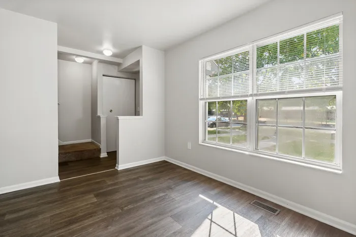 Bright and inviting room with large windows, modern wood flooring, and cozy entryway.
