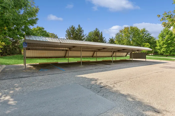 Inviting covered parking area nestled in a tranquil setting with lush green surroundings and an accessible parking space.
