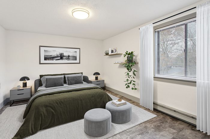 Elegant bedroom with a modern green and grey theme, featuring a cozy bed, stylish decor, and abundant natural light from a large window.