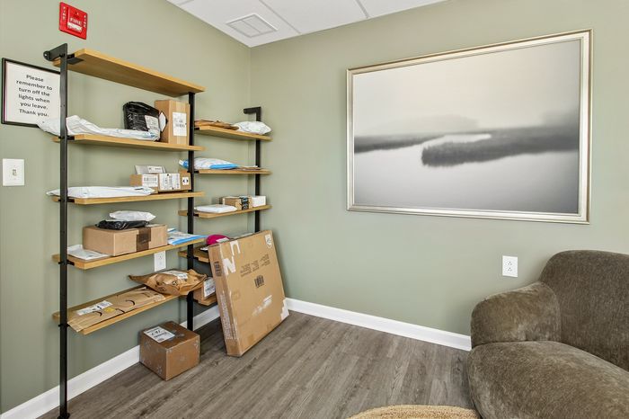 Inviting storage room featuring sleek open shelving with neatly organized packages and modern art on a soothing green wall.