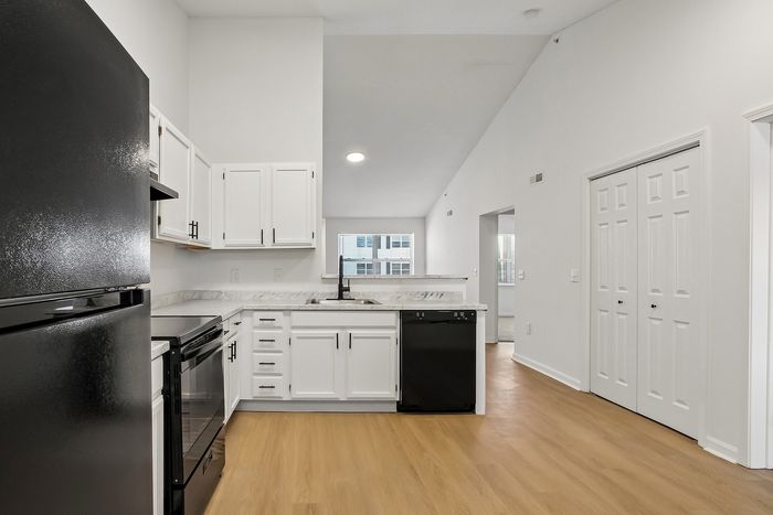Modern kitchen with sleek black appliances, white cabinetry, and spacious countertops, featuring a natural light-filled ambiance.
