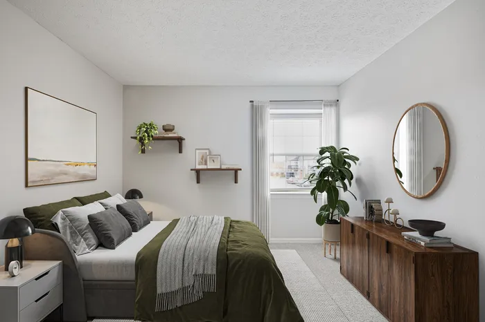 Bright and cozy bedroom featuring modern decor, plush bedding in green tones, and charming natural light from a large window.