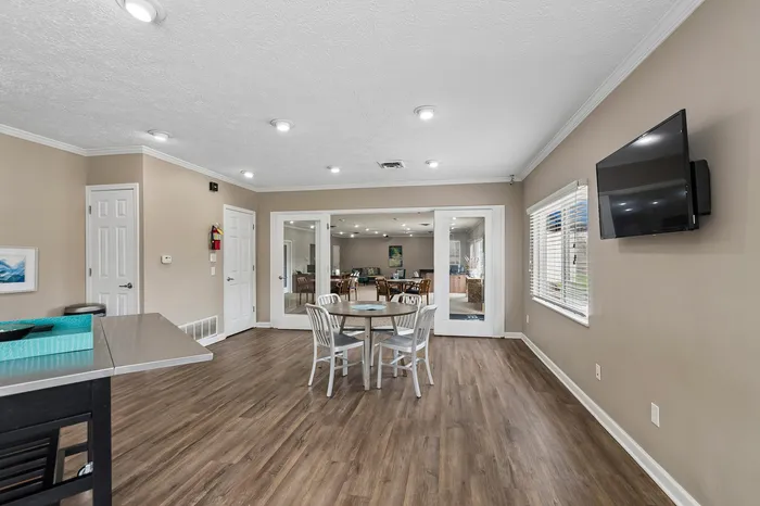 Bright open-concept living area with wood flooring, a mounted TV, and modern dining set, perfect for entertaining.