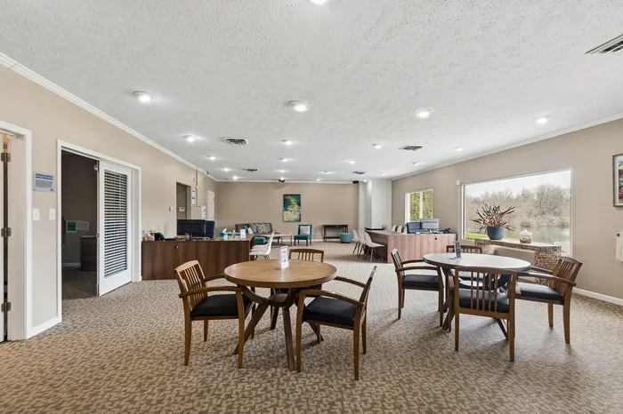 Inviting and spacious communal area with modern seating, large windows offering serene nature views, and stylish decor.