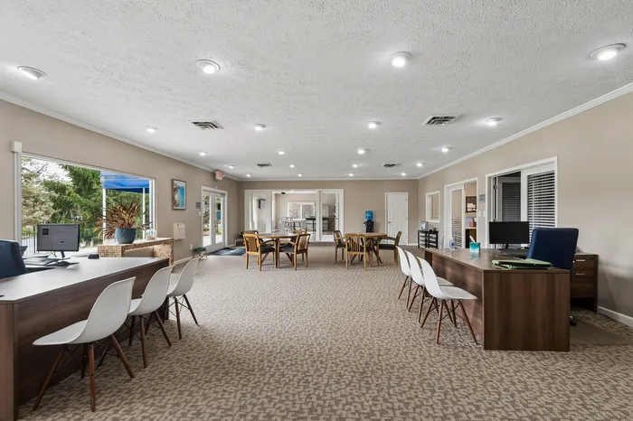 Elegant open-concept community room with cozy seating, ample natural light, and modern workstations, perfect for gatherings or remote work.