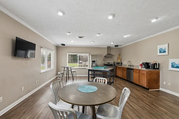 Modern open kitchen and dining area featuring sleek stainless steel appliances, stylish wooden cabinetry, and an inviting dining table with a view of large windows for natural light.