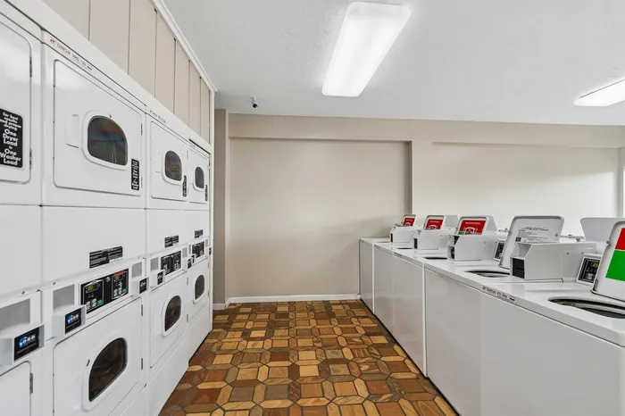 Modern laundry room with multiple washers and dryers, featuring bright lighting and stylish patterned flooring.