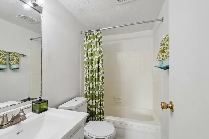 Inviting bathroom with fresh green decor, featuring a pristine white bathtub and modern vanity.