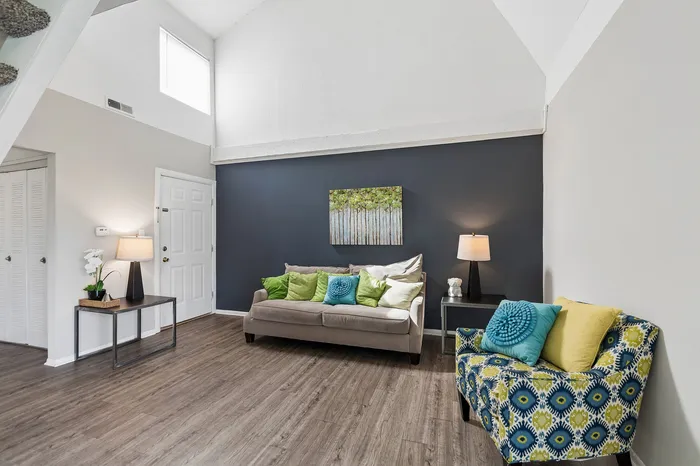 Chic living room with high ceilings featuring modern decor, plush seating, and elegant lighting against a stylish accent wall.