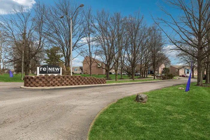 Charming suburban entrance showcasing ReNew community with lush green lawns and welcoming pathways.