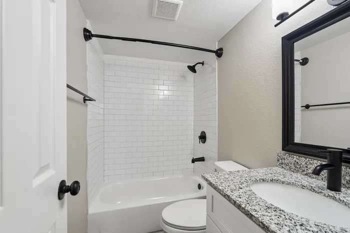 Modern bathroom featuring elegant subway tile, a sleek granite vanity, and matte black fixtures for a chic design.