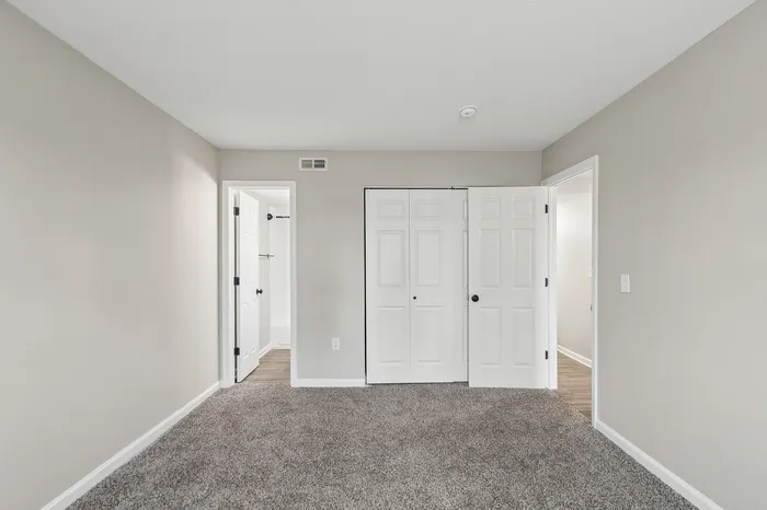 Bright bedroom featuring plush carpeting, a spacious closet with double doors, and an en-suite bathroom for added convenience.