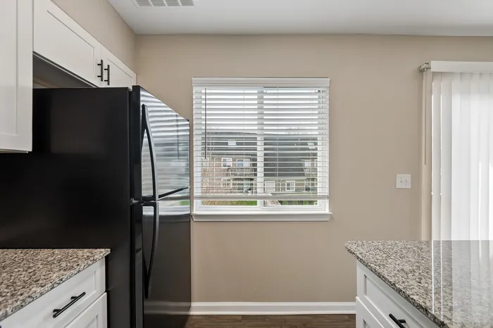 Modern kitchen with granite countertops, black appliances, and a large window allowing natural light to enhance the space.