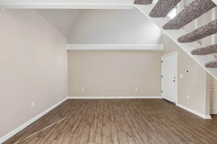 Bright and inviting room featuring elegant wood flooring and modern staircase design, ideal for any stylish home interior.