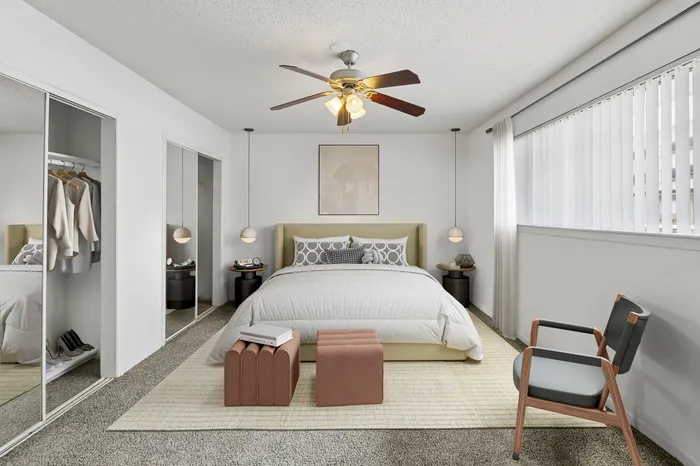 Elegant bedroom with plush bedding, mirrored closets, stylish decor, and ample natural light.