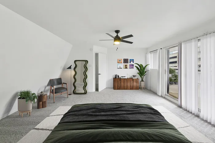 Spacious and bright bedroom with modern decor, stylish furniture, and large windows opening to a private balcony.