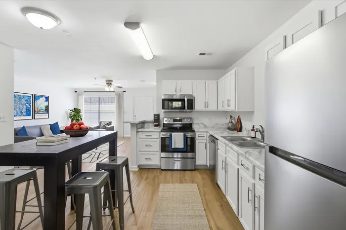 Bright and modern kitchen with sleek stainless steel appliances, elegant white cabinetry, and a cozy open-concept living space with stylish decor.