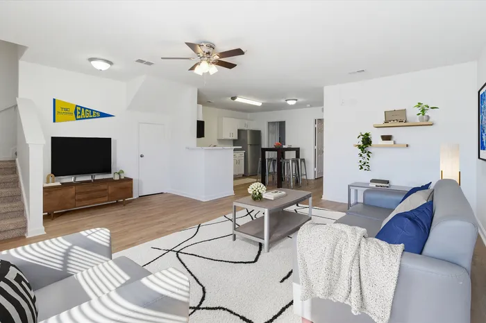 Bright and modern living room with open kitchen, stylish decor, and natural light streaming through the windows.