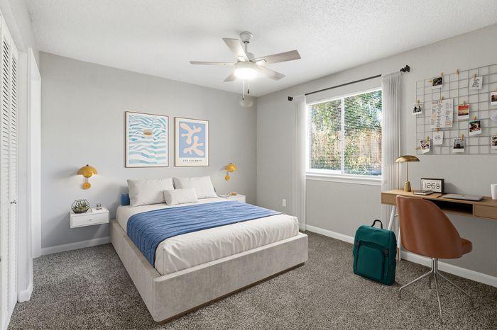 Bright and inviting bedroom featuring cozy decor, a comfortable bed with blue accents, modern artwork, and ample natural light from a large window.