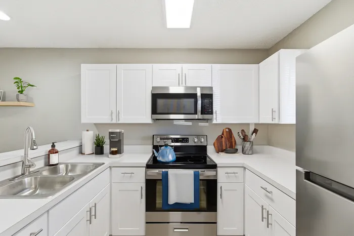 Modern kitchen with sleek stainless steel appliances, white cabinetry, and elegant countertops offering a stylish and functional cooking space.