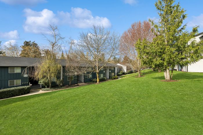 Charming apartment complex surrounded by lush greenery and vibrant trees, offering serene living in a picturesque setting.