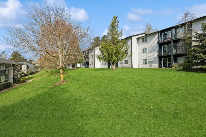 Charming apartment complex surrounded by lush greenery and mature trees, offering a serene and inviting atmosphere.